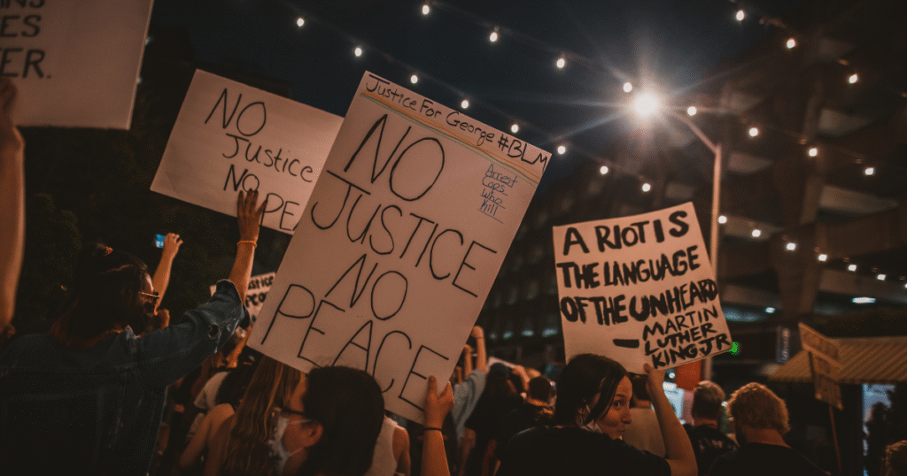 imagem de protesto de antirracismo com várias pessoas segurando cartazes