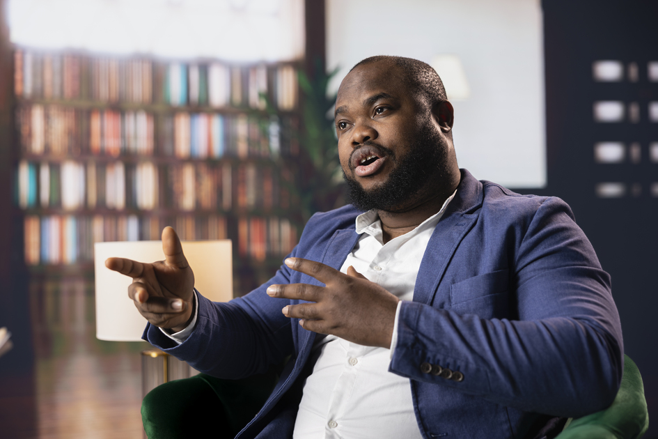 imagem de homem negro com expressão séria explicando sobre algo, em artigo sobre racismo no ambiente de trabalho